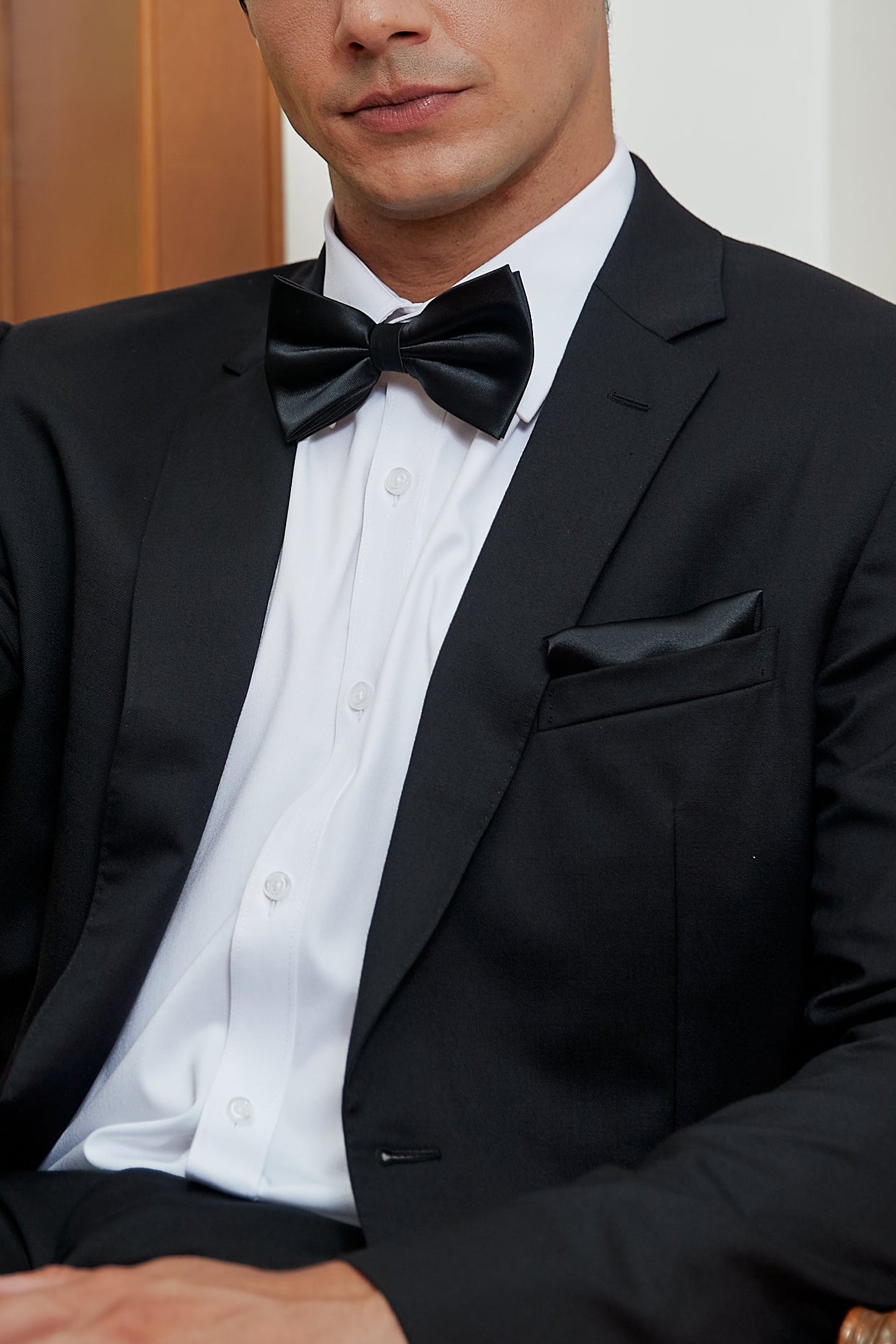 Man in a black bow tie sitting on a chair indoors