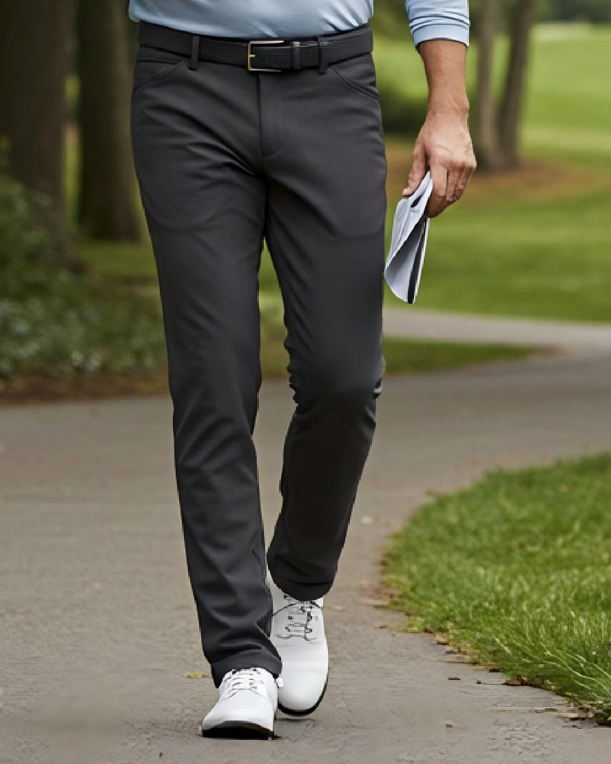 Person wearing gray pants and white shoes walking on a path outdoors.