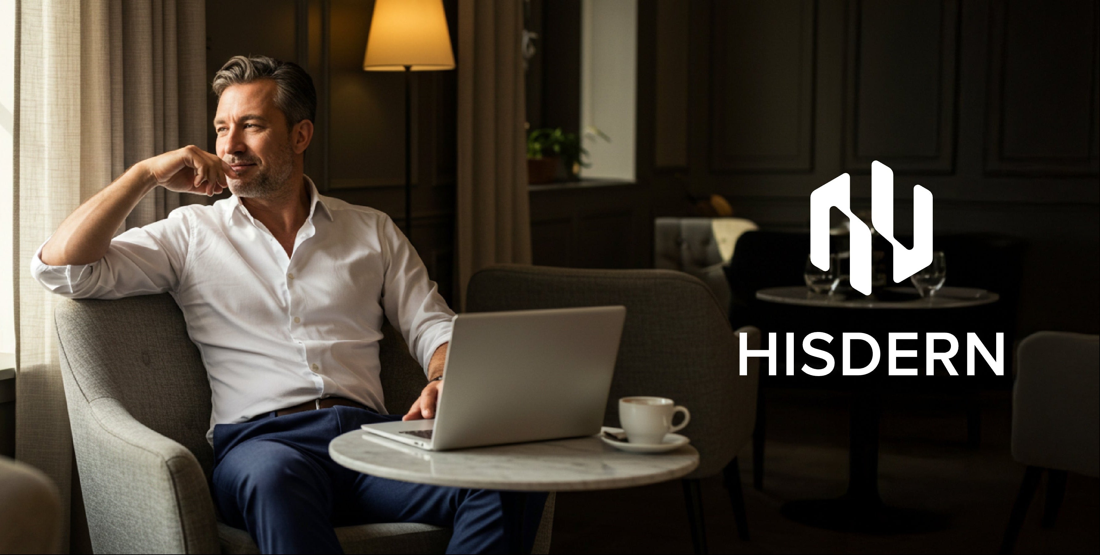 Man using a laptop in a modern living room with 'HISDERN' branding.